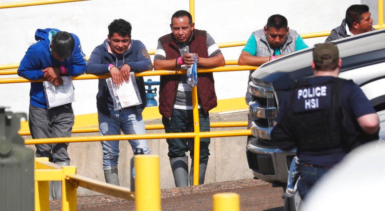 Handcuffed workers await transportation to a processing center following a raid by U.S. immigration officials at Koch Foods Inc., plant in Morton, Miss. (AP Photo/Rogelio V. Solis)