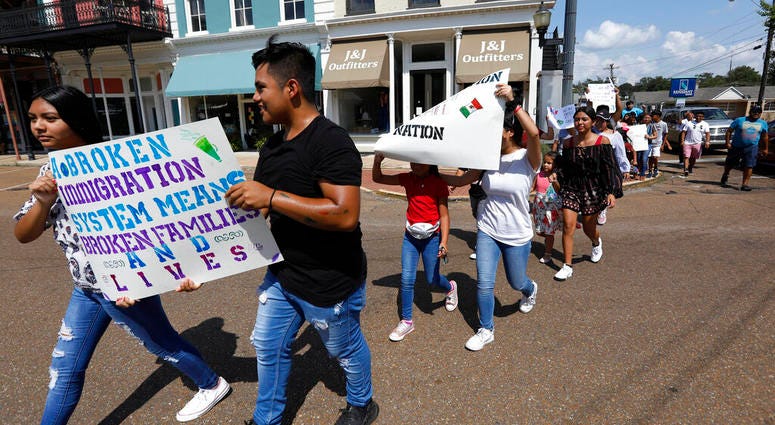 In this Aug. 11, 2019 photo, children of mainly Latino immigrant parents hold signs in support of them and those individuals picked up during an immigration raid at a food processing plant in Canton, Miss. (AP Photo/Rogelio V. Solis)