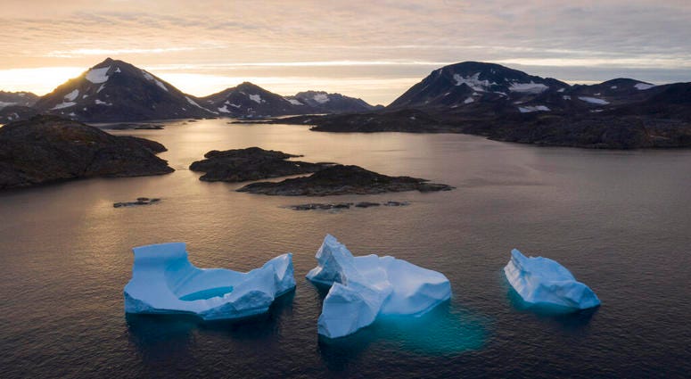 In this Aug. 15, 2019, photo, a boat navigates at night next to large icebergs in eastern Greenland. Greenland's ice has been melting for more than 20 years. (AP Photo/Felipe Dana)