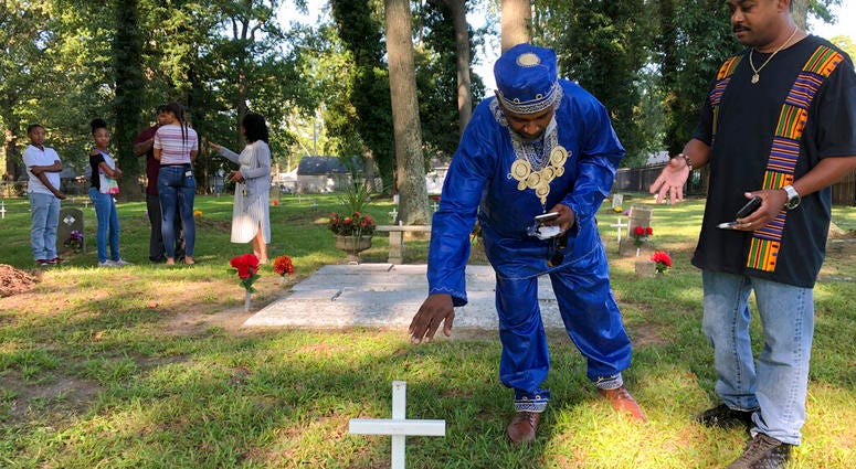 Andre Bradshaw, left, and Eric Jackson stand at an unmarked grave at the Tucker Family Cemetery in Hampton, Va. on Friday, Aug. 23, 2019. They are part of a larger family that traces its roots back to the first enslaved Africans to arrive in what is now V