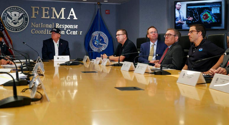 President Donald Trump, left, listens as Kenneth Graham, director of NOAA's National Hurricane Center, on screen, gives an update during a briefing about Hurricane Dorian at FEMA, Sunday, Sept. 1, 2019. (AP Photo/Jacquelyn Martin)