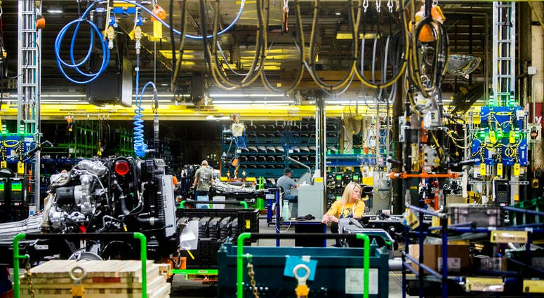 FILE - In this June 12, 2019, file photo General Motors employees work on the chassis line as they build the frame, power train and suspension onto the truck's body at the Flint Assembly Plant in Flint, Mich.