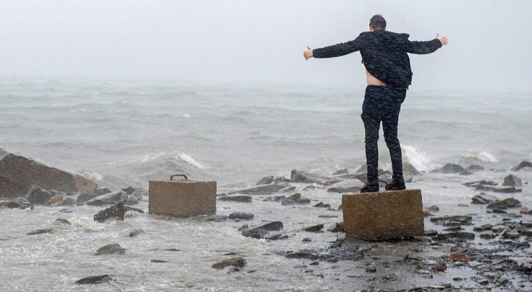 An unidentified man raises his arms in the winds from Hurricane Dorian along the Halifax harbor in Dartmouth, Nova Scotia, Canada, on Saturday, Sept. 7, 2019. (Andrew Vaughan/The Canadian Press via AP)
