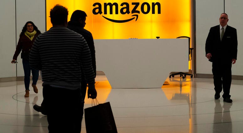 FILE - In this Feb. 14, 2019, file photo people walk into the lobby for Amazon offices in New York. The online shopping giant is holding job fairs across the country next week, aiming to hire more than 30,000 people by early next year, a 5% bump in its to