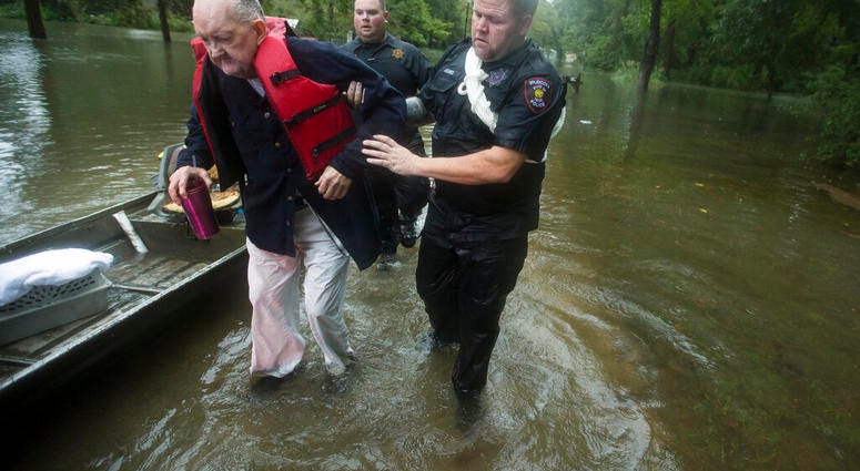 Fred Stewart, left, is helped to high ground after he was rescued from his flooded neighborhood as rains from Tropical Depression Imelda inundated the area, Thursday, Sept. 19, 2019, in Splendora, Texas. (Brett Coomer/Houston Chronicle via AP)