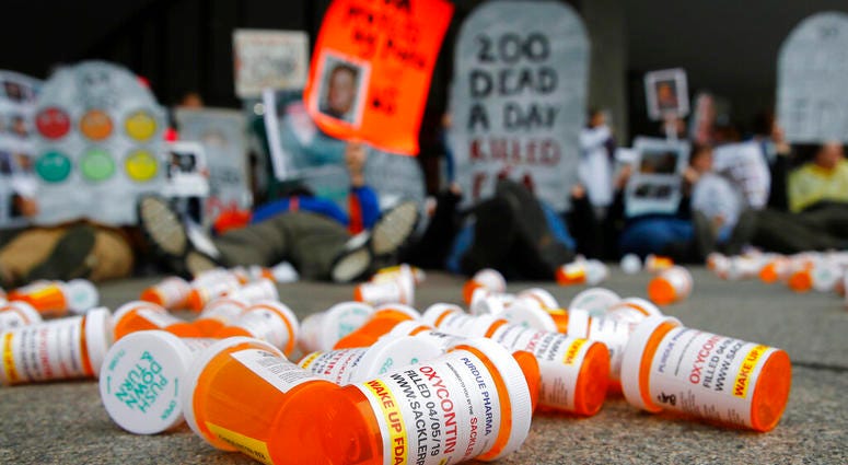 FILE - In this April 5, 2019, file photo, containers depicting OxyContin prescription pill bottles lie on the ground in front of the Department of Health and Human Services' headquarters in Washington. (AP Photo/Patrick Semansky, File)