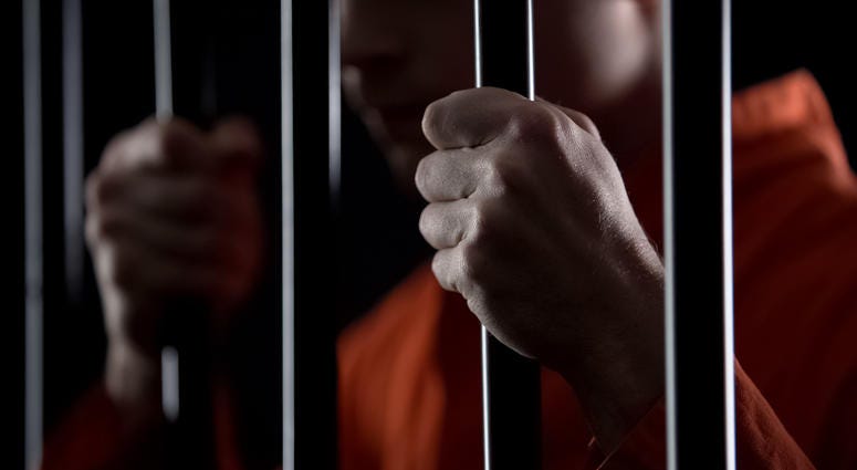 criminal holding jail bars feeling regret for committing crime closeup