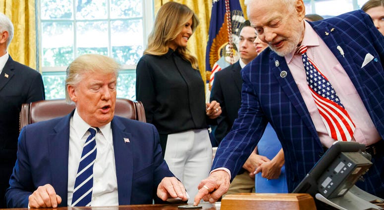 President Donald Trump receives a gift from Apollo 11 astronaut Buzz Aldrin, with first lady Melania Trump, during a photo opportunity commemorating the 50th anniversary of the Apollo 11 moon landing in the Oval Office. (AP Photo/Alex Brandon)