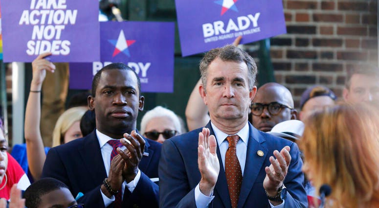 Virginia Gov. Ralph Northam, right, applauds speakers along with Richmond Mayor Levar Stoney, left, during a rally at the State Capitol in Richmond, Va., Tuesday, July 9, 2019. (AP Photo/Steve Helber)