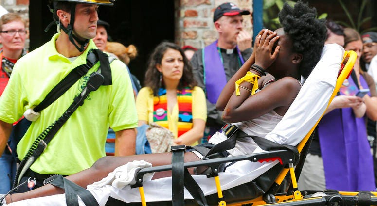 FILE - In this Aug. 12, 2017, file photo, an emergency employee helps an injured person after a neo-Nazi drove his car into a group of counter-protesters at a white nationalist rally in Charlottesville, Va. (AP Photo/Steve Helber, File)