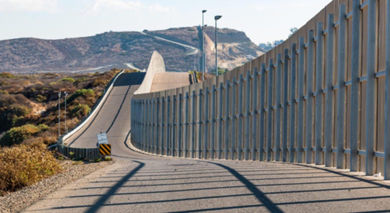 The international border wall between San Diego, California and Tijuana, Mexico, as it begins its journey from the Pacific coast and travels over nearby hills.