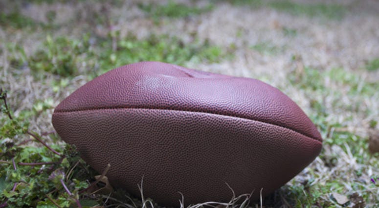 Football that is very low on air on a grassy field