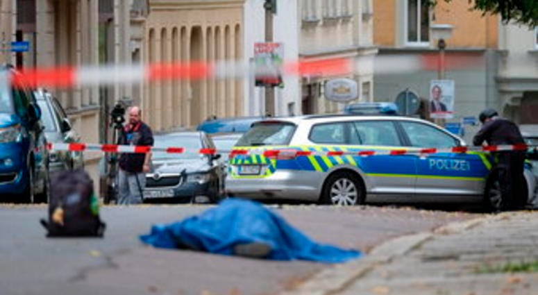 A person lies on a road in Halle, Germany, Wednesday, Oct. 9, 2019. A gunman fired several shots on Wednesday in German city of Halle and at least two got killed, according to local media FOCUS online. (Sebastian Willnow/dpa via AP)