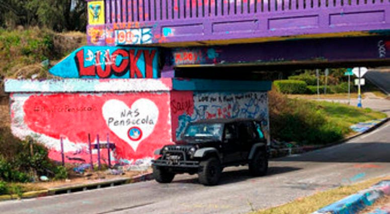 A vehicle drives by a tribute to victims of the Naval Air Station Pensacola that was freshly painted on what’s known as Graffiti Bridge in downtown Pensacola, Fla., on Saturday, Dec. 7, 2019. (AP Photo/Brendan Farrington) A vehicle drives by a tribute to victims of the Naval Air Station Pensacola that was freshly painted on what’s known as Graffiti Bridge in downtown Pensacola, Fla., on Saturday, Dec. 7, 2019. (AP Photo/Brendan Farrington)