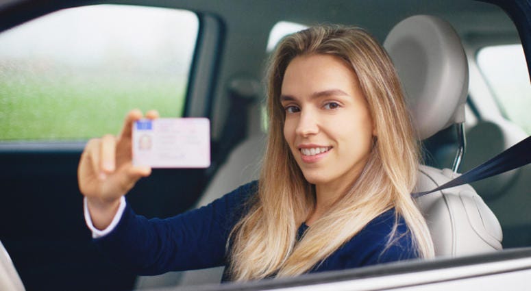 Woman smiling with driving license. (iStock / Getty Images Plus)