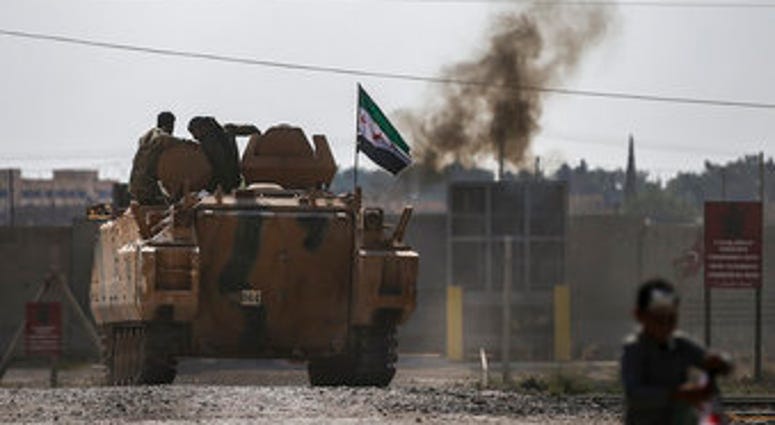 Turkish-backed Syrian opposition fighters on an armoured personnel carrier drive to cross the border into Syria, in Akcakale, Sanliurfa province, southeastern Turkey. (AP Photo/Emrah Gurel)