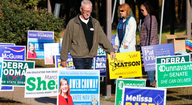 Voters walk through a sea of campaign signs at a polling station in Richmond, Va., Tuesday, Nov. 5, 2019. All seats in the Virginia House of Delegates and State senate are up for election. (AP Photo/Steve Helber)