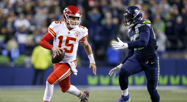 Dec 23, 2018; Seattle, WA, USA; Kansas City Chiefs quarterback Patrick Mahomes (15) scrambles against Seattle Seahawks defensive end Frank Clark (55) during the third quarter at CenturyLink Field. Mandatory Credit: Joe Nicholson-USA TODAY Sports