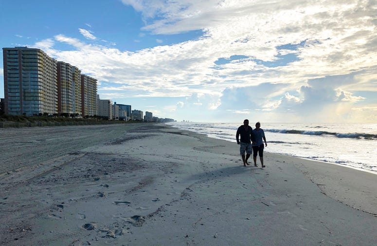 Chris and Nicole Roland walk down a beach in North Myrtle Beach, S.C. on Wednesday, Sept. 12, 2018. The couple boarded up their uncle's condominium and are leaving soon as Hurricane Florence approaches Chris and Nicole Roland walk down a beach in North Myrtle Beach, S.C. on Wednesday, Sept. 12, 2018. The couple boarded up their uncle's condominium and are leaving soon as Hurricane Florence approaches
