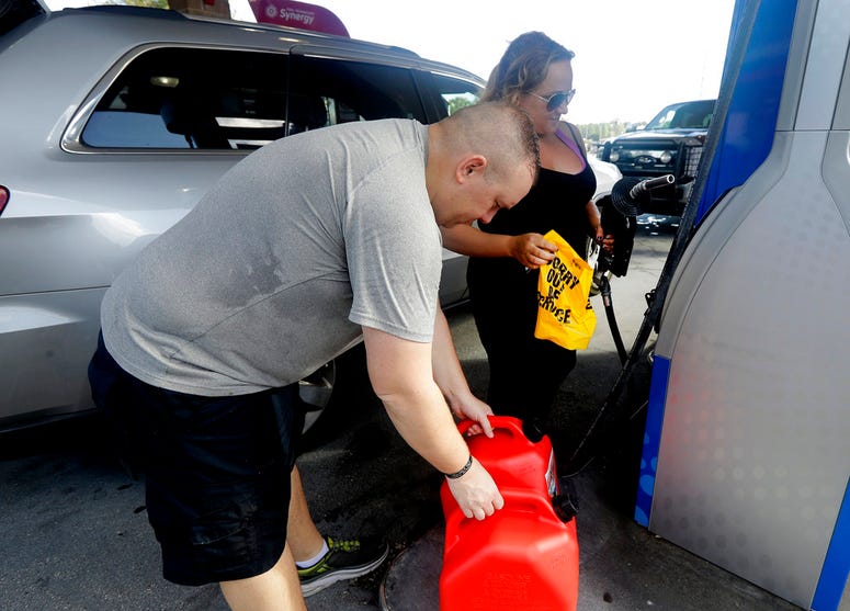Sarah Dankanich, right, removes an "out of service" wrapper from a gas pump as her husband, Bryan Dankanich, left, prepares to pump gas in cans in advance of Hurricane Florence in Wilmington, N.C., Wednesday, Sept. 12, 2018. Florence exploded into a poten Sarah Dankanich, right, removes an "out of service" wrapper from a gas pump as her husband, Bryan Dankanich, left, prepares to pump gas in cans in advance of Hurricane Florence in Wilmington, N.C., Wednesday, Sept. 12, 2018. Florence exploded into a poten