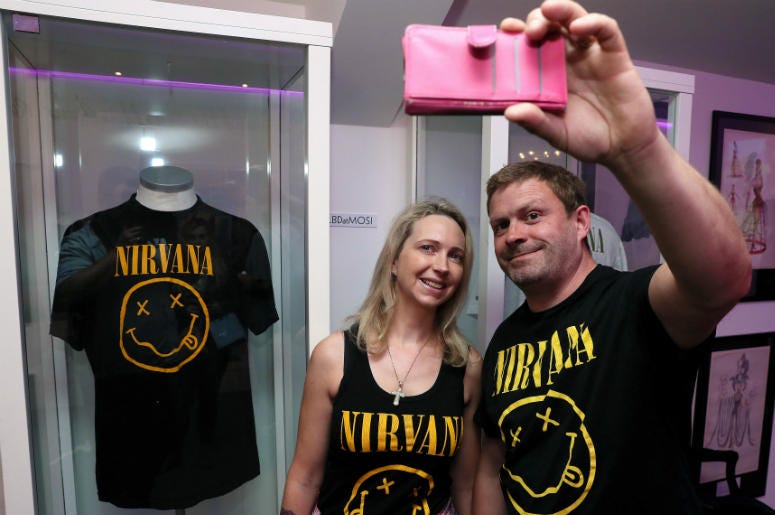 Nirvana fans Tanya and Dave Deegan, from Dublin, take a picture alongside Kurt Cobain's Nirvana smiley face t-shirt at the opening of the 'Growing Up Kurt' exhibition on the life of the Nirvana frontman, at the museum of Style Icons in Newbridge, Ireland. Nirvana fans Tanya and Dave Deegan, from Dublin, take a picture alongside Kurt Cobain's Nirvana smiley face t-shirt at the opening of the 'Growing Up Kurt' exhibition on the life of the Nirvana frontman, at the museum of Style Icons in Newbridge, Ireland.