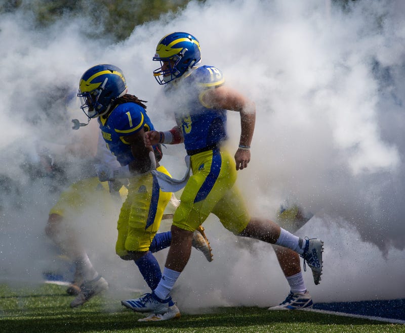 Members of the University of Delaware Blue Hens running onto the football field.