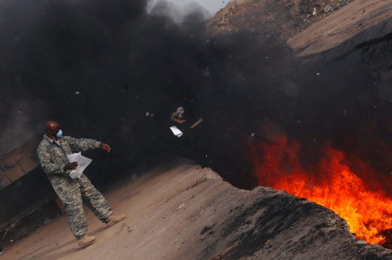 Master Sgt. Darryl Sterling, 332nd Expeditionary Logistics Readiness Squadron equipment manager, tosses unserviceable uniform items into a burn pit, March 10, 2008.