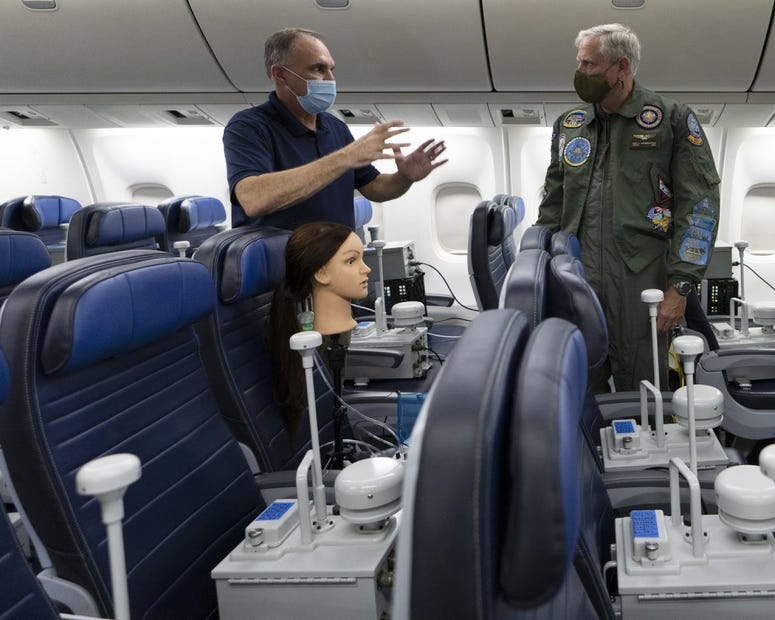 Vice Adm. Dee Mewbourne (right), deputy commander, U.S. Transportation Command, receives a description of the airflow particle test from David Silcott (left), chief executive of S3i, a biological research company, on board a United Airlines 767 aircraft.