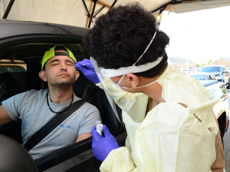 Captain James A. Lovell Federal Health Care Center Hospitalman Recruit Yavir Berrios-Santiago collects a nasal swab from a Naval Station Great Lakes Recruit Training Command employee during drive-through COVID-19 screening at Lovell FHCC in North Chicago.