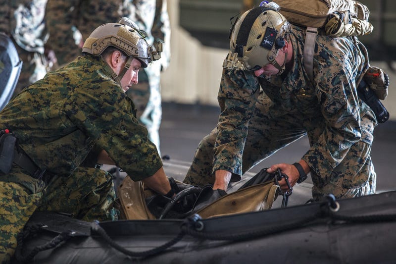 Marines pack equipment in a combat rubber raiding craft in preparation for search and rescue operations