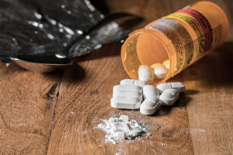Oxycodone is the generic name for a range of opoid pain killing tablets. Prescription bottle for Oxycodone tablets and pills on wooden table for opioid epidemic illustration