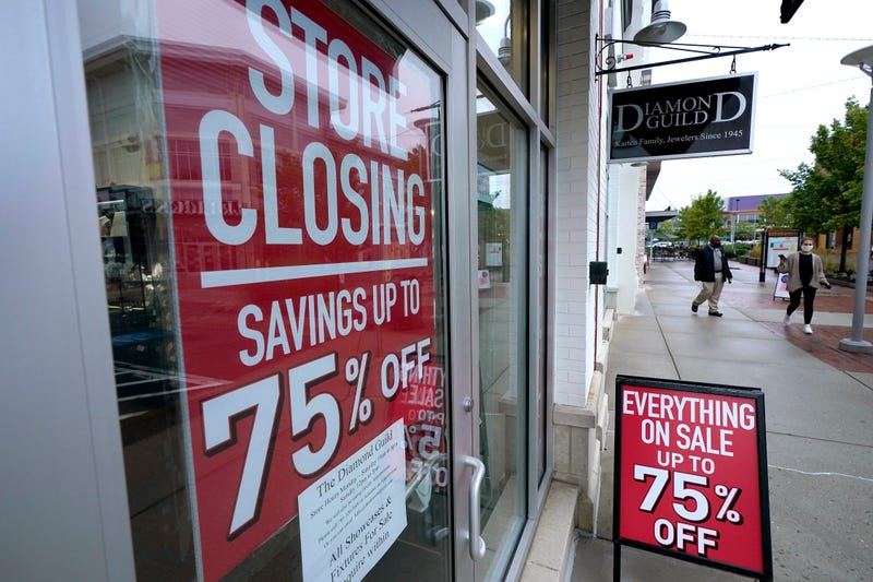 In this Wednesday, Sept. 2, 2020, file photo, passers-by walk past a business storefront with store closing and sale signs in Dedham, Mass.