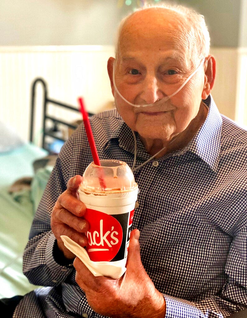 In this photo provided by Holly Wooten McDonald, World War II veteran and COVID-19 survivor Major Wooten holds a celebratory milkshake on his 104th birthday