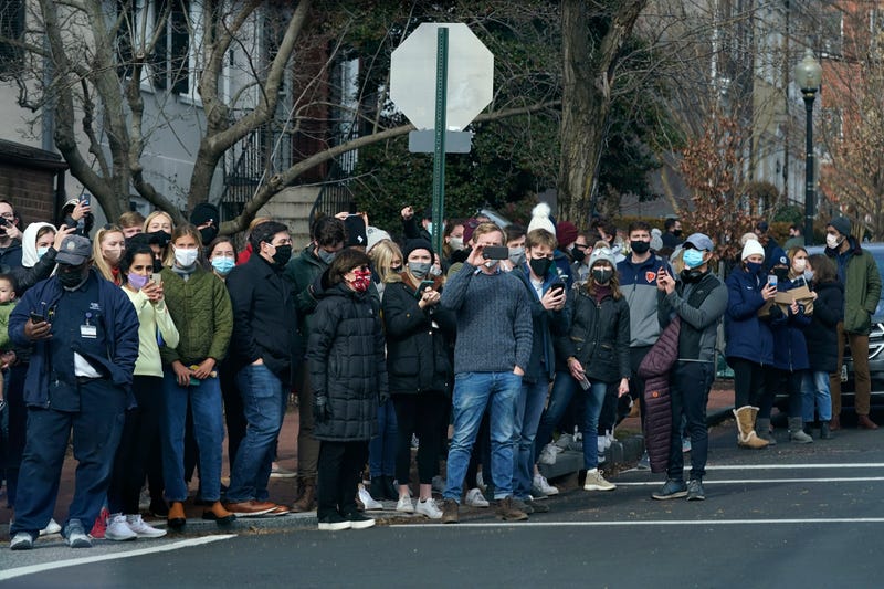 People gather to watch as President Joe Biden's motorcade departs Holy Trinity Catholic Church, Sunday, Jan. 24, 2021, in the Georgetown neighborhood of Washington.