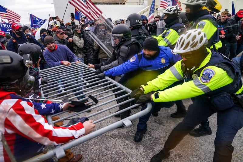 In this Jan. 6, 2021, file photo violent insurrectionists loyal to President Donald Trump supporters try to break through a police barrier at the Capitol in Washington. A month ago, the U.S. Capitol was besieged by Trump supporters angry about the former president's loss. While lawmakers inside voted to affirm President Joe Biden's win, they marched to the building and broke inside. (AP Photo/John Minchillo, File)