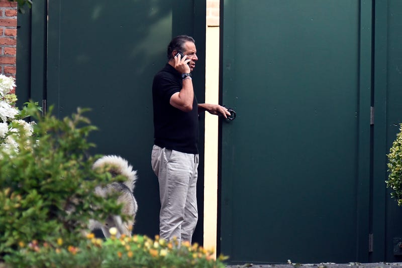 Gov. Andrew Cuomo talks on the phone while walking with his dog Captain at the New York state Executive Mansion, Saturday, Aug. 7, 2021, in Albany, N.Y