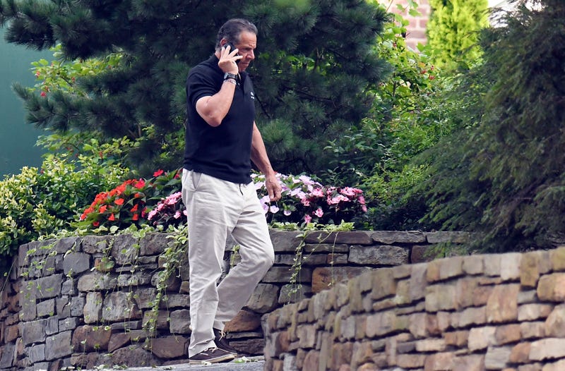 Gov. Andrew Cuomo talks on the phone while walking with his dog Captain at the New York state Executive Mansion, Saturday, Aug. 7, 2021, in Albany, N.Y