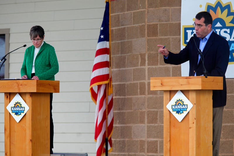Kansas Attorney General Derek Schmidt, right, the Republican nominee for governor, makes a point during a debate as Democrat Gov. Laura Kelly watches at the Kansas State Fair.