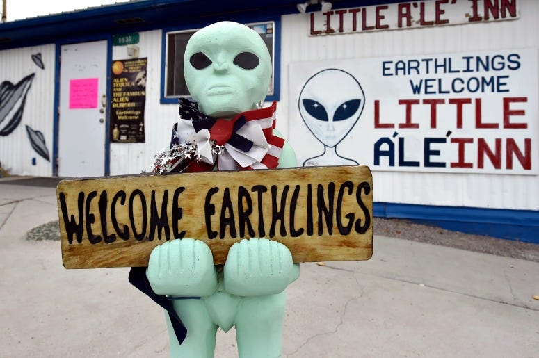 An alien-like statue displays a sign welcoming guests