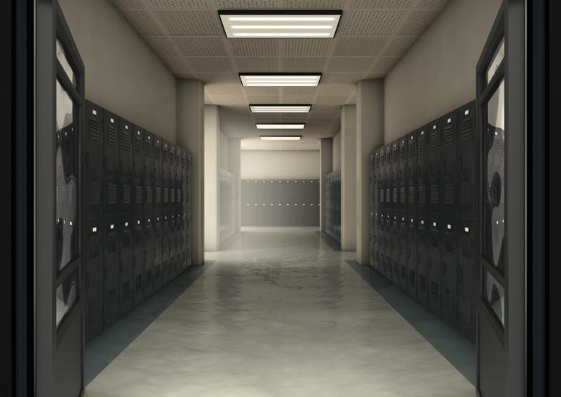 A look down a dimly lit hallway of school lockers