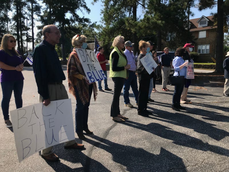 Crowd holds signs during AG Wilson's remarks