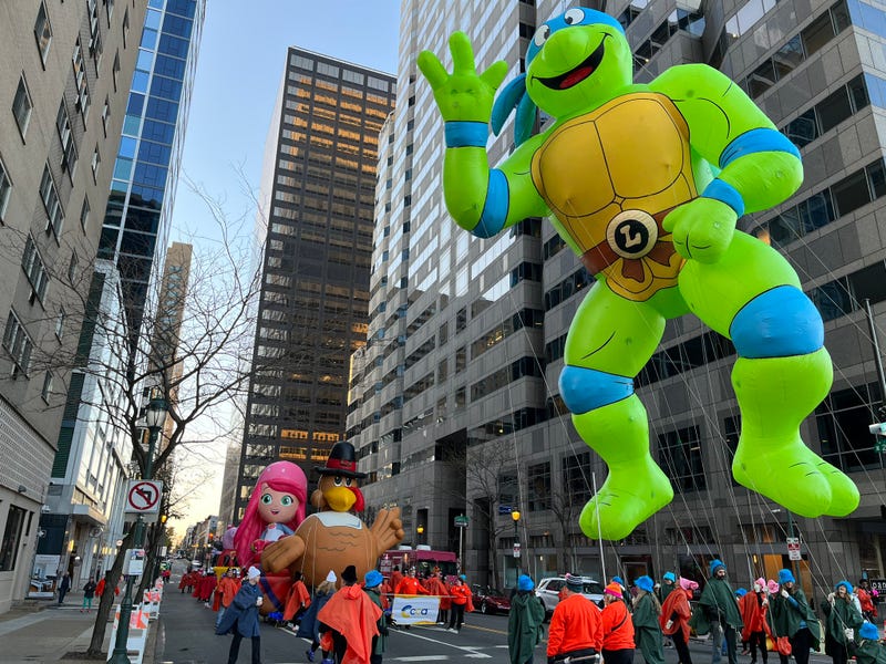 A team holding down a balloon figure of Teenage Mutant Ninja Turtle Leonardo waits for the 103rd Thanksgiving Day Parade to start.