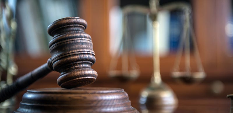 A judge's gavel, with the Scales of Justice in the background