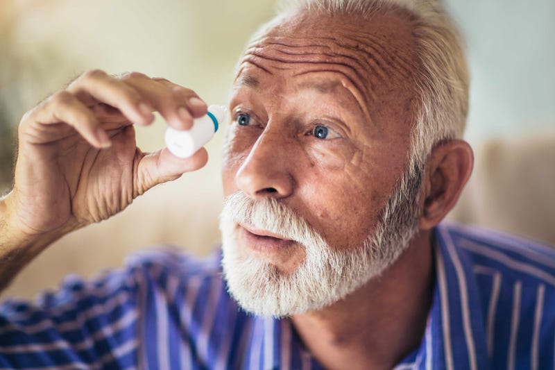 An old man uses eye drops