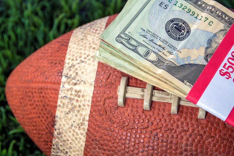 Football with a stack of cash on top.