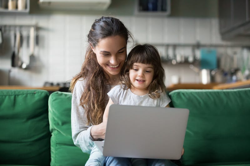 A smiling mother and daughter use a laptop together