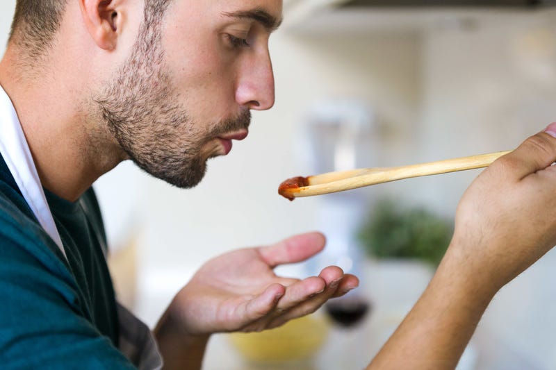 A man tests tomato sauce as he cooks
