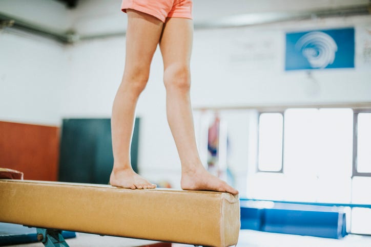 Young gymnast balancing on a balance beam