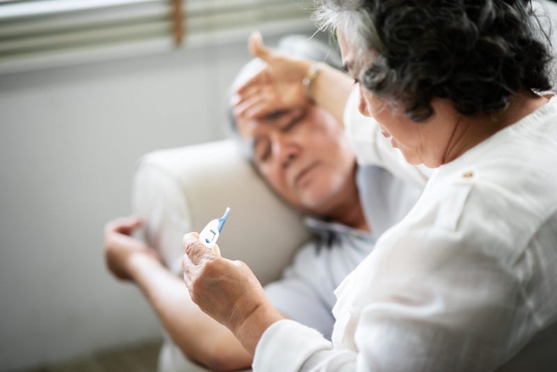 An old woman checks an old man's temperature