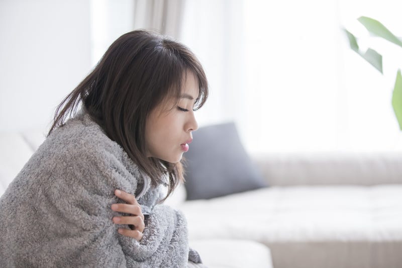 Woman in a blanket feels sick